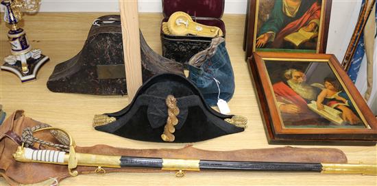 A bicorn hat and tin, matching epaulettes in a tin and a ceremonial sword and holster. Circa 1900.